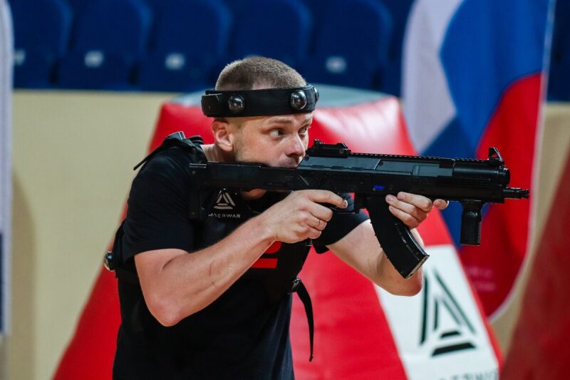 Игрок LASERWAR с автоматом у красного укрытия в полной готовности.
